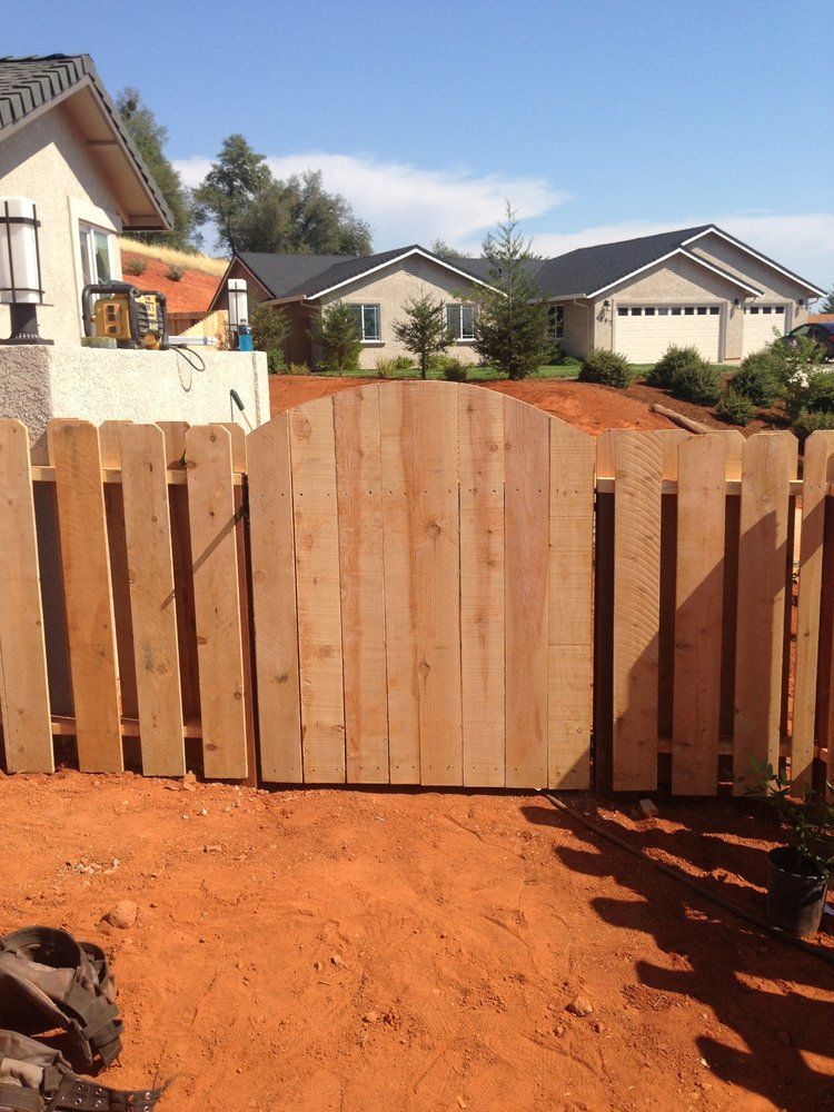 Wooden backyard fence and gate in a residential yard with houses in the background