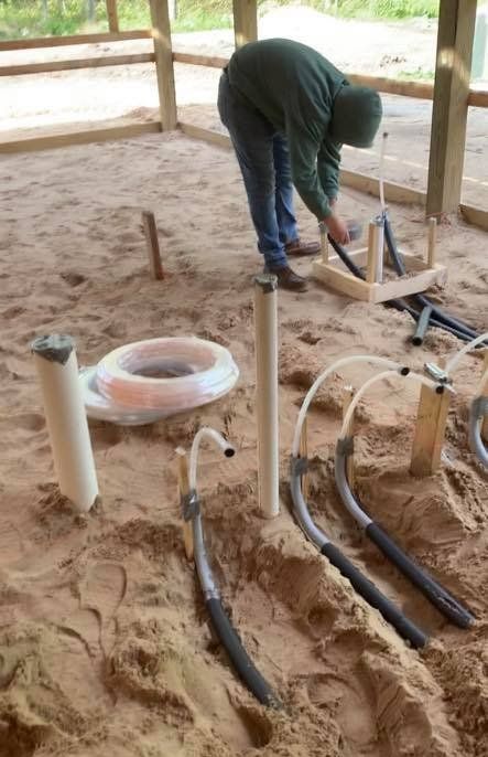 A man is working on a pipe system in the dirt.