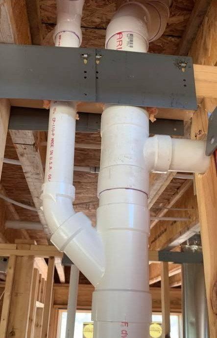 A bunch of white pipes are stacked on top of each other in a building under construction.
