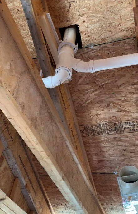 A white pipe is hanging from the ceiling of a wooden structure.