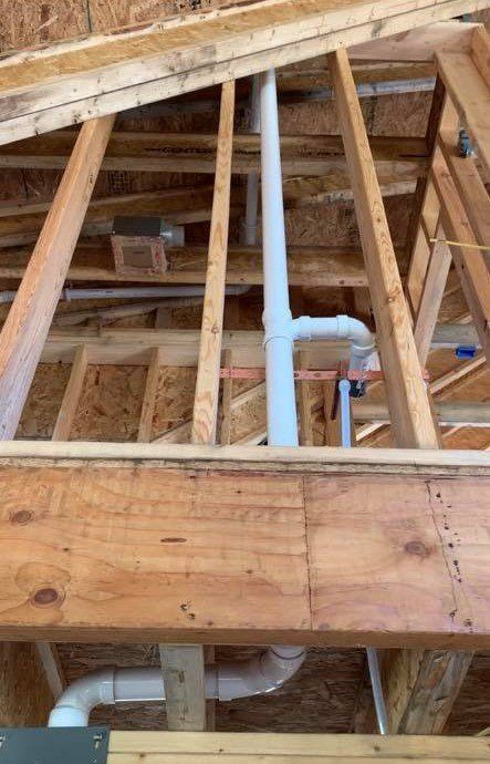A picture of a house under construction with pipes coming out of the ceiling.