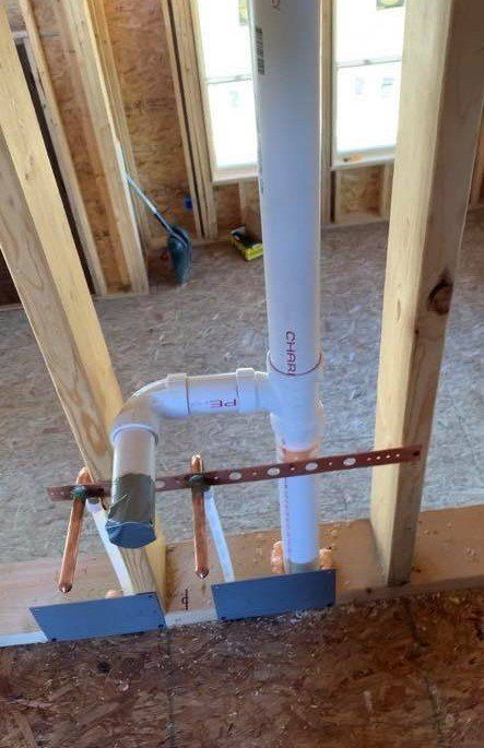 A pvc pipe is being installed in a house under construction.