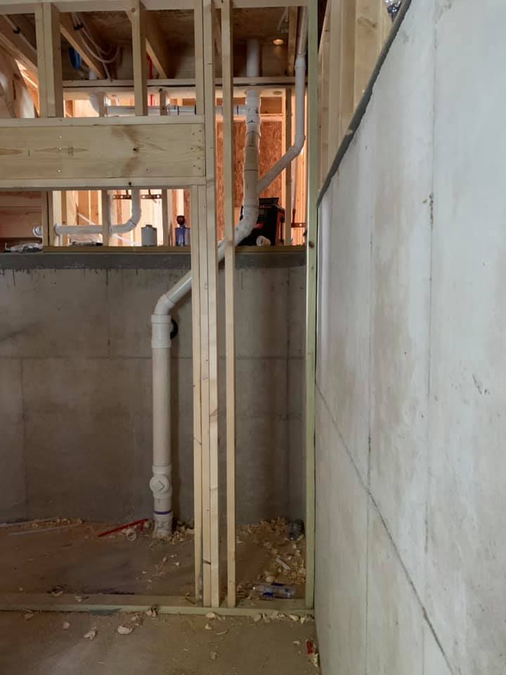 A basement under construction with pipes coming out of the wall.