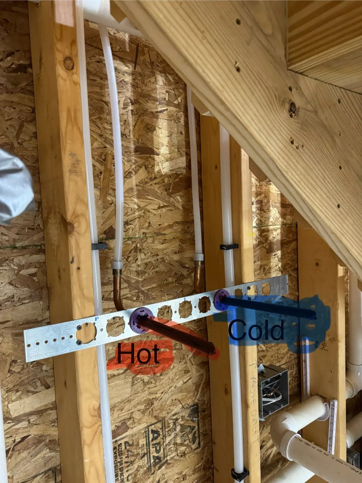 Pipes for hot/cold water, bracketed to wooden studs in a wall. Text labels indicate the hot and cold lines.