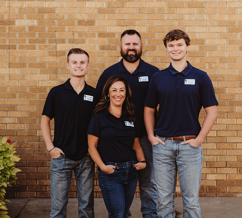 A gray tankless water heater in a basement, with pipes and electrical wiring.