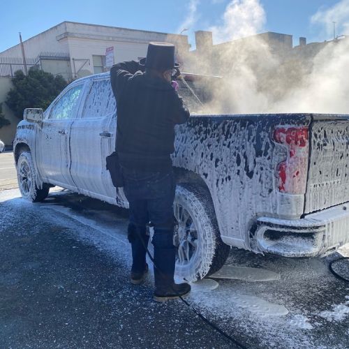 A man in a top hat is washing a truck