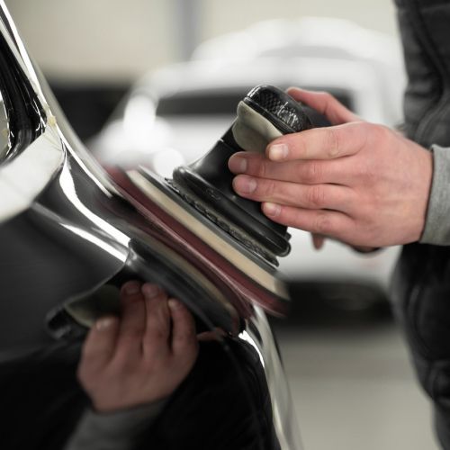 A person is polishing a car with a sander
