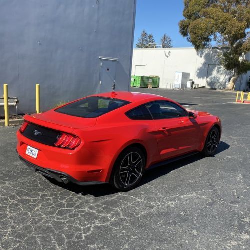 A red ford mustang is parked in a parking lot