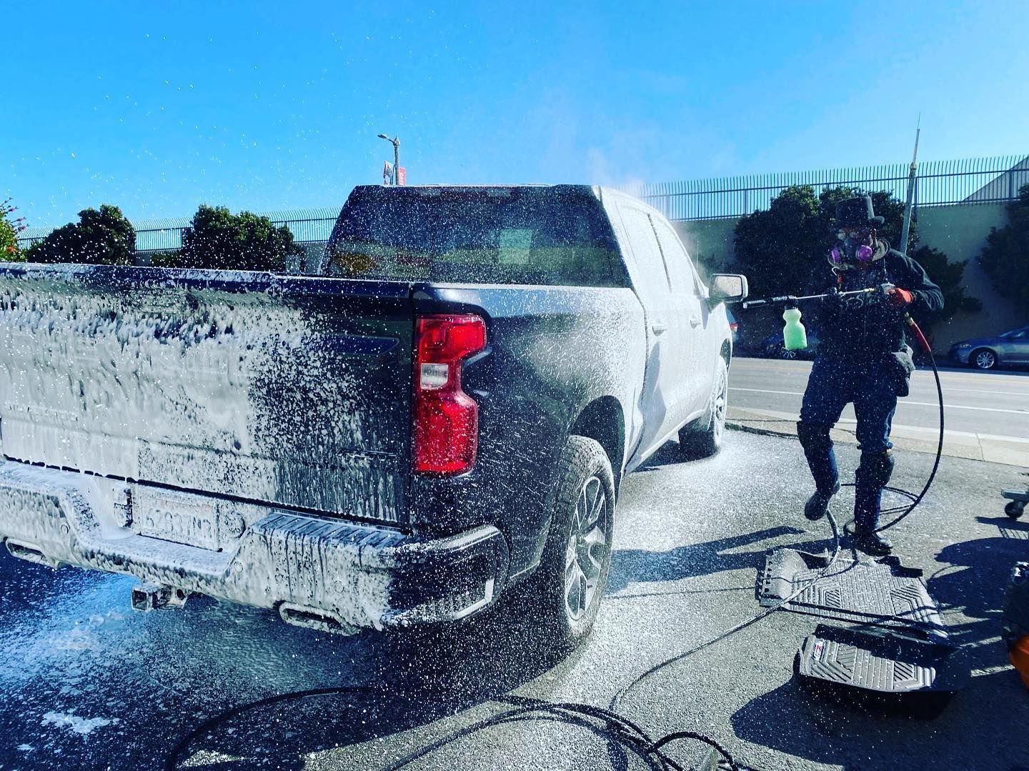 A man is washing a truck with a high pressure washer.