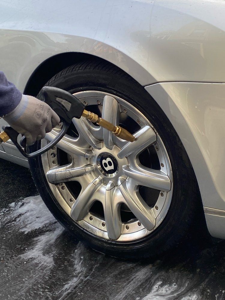 A bentley wheel is being cleaned with a high pressure washer