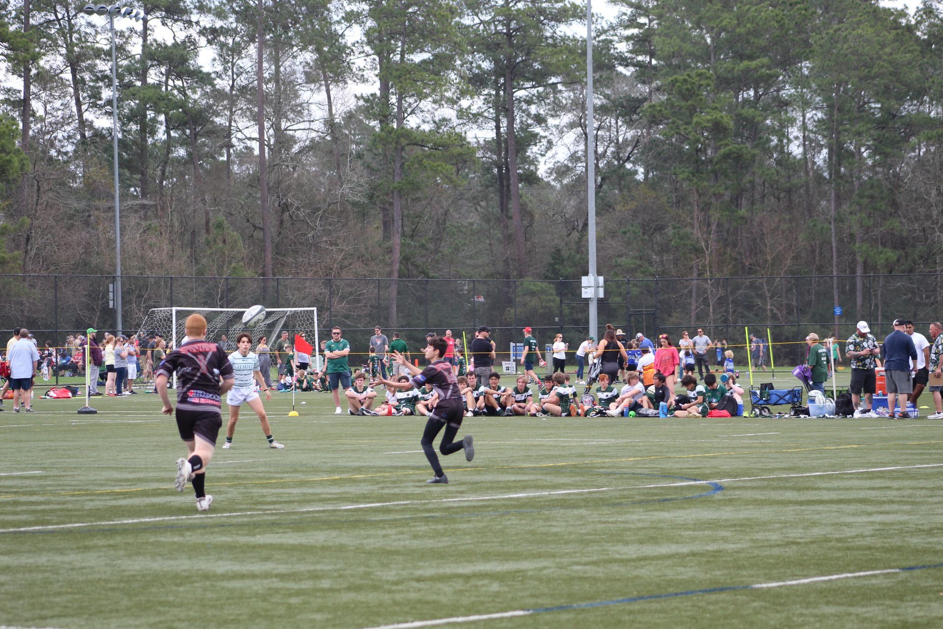 Ultimate frisbee game on a green field. Players running, spectators watching.
