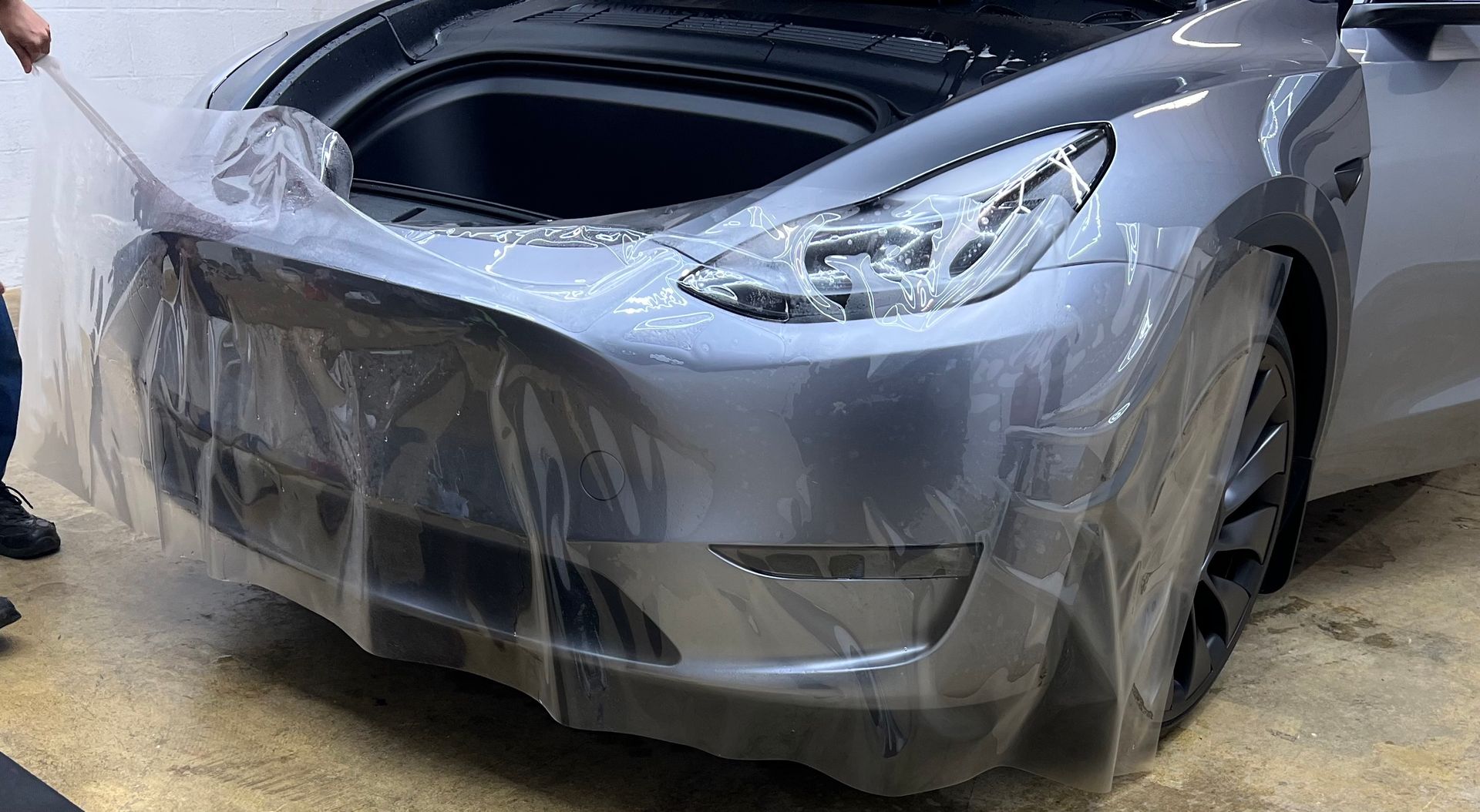A tesla model 3 is being wrapped in plastic.