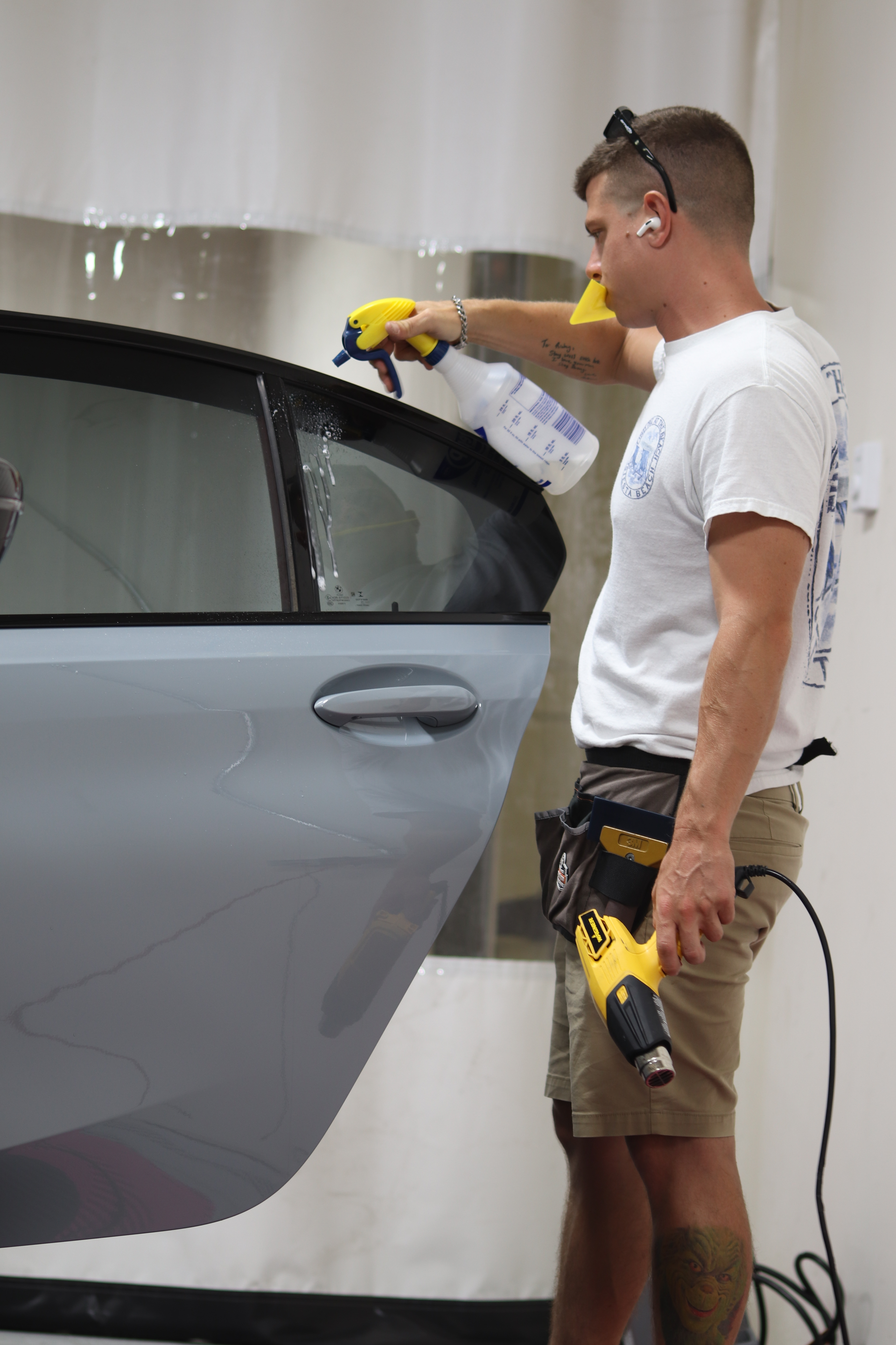 A man is spraying a car window with a spray bottle