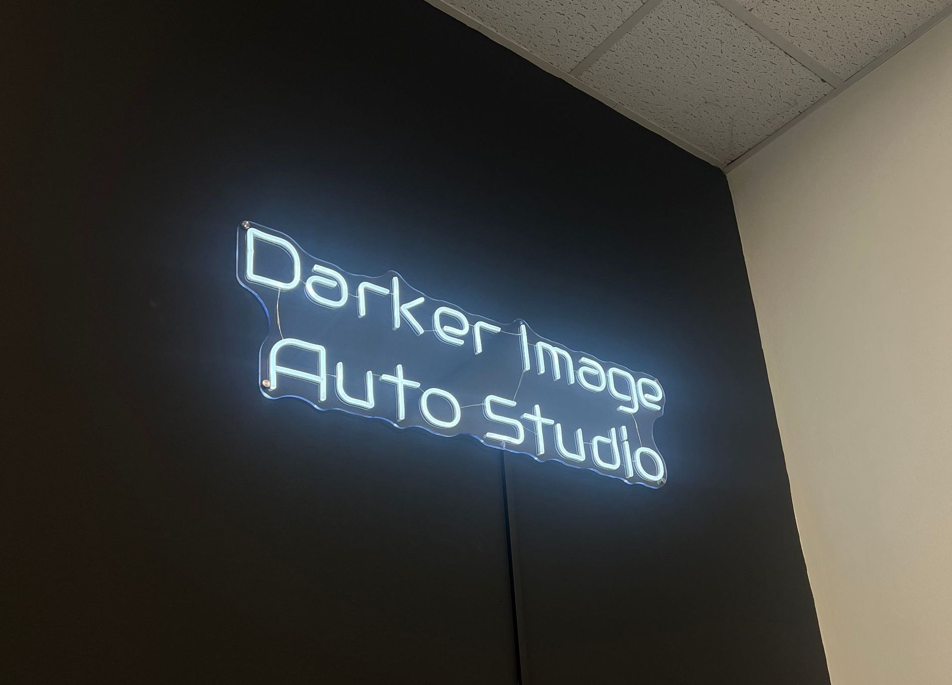 A person is applying a protective film to a red car.