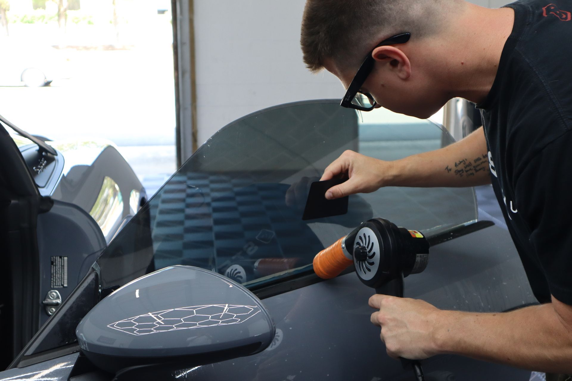 Person using a buffer to polish a black car in a garage