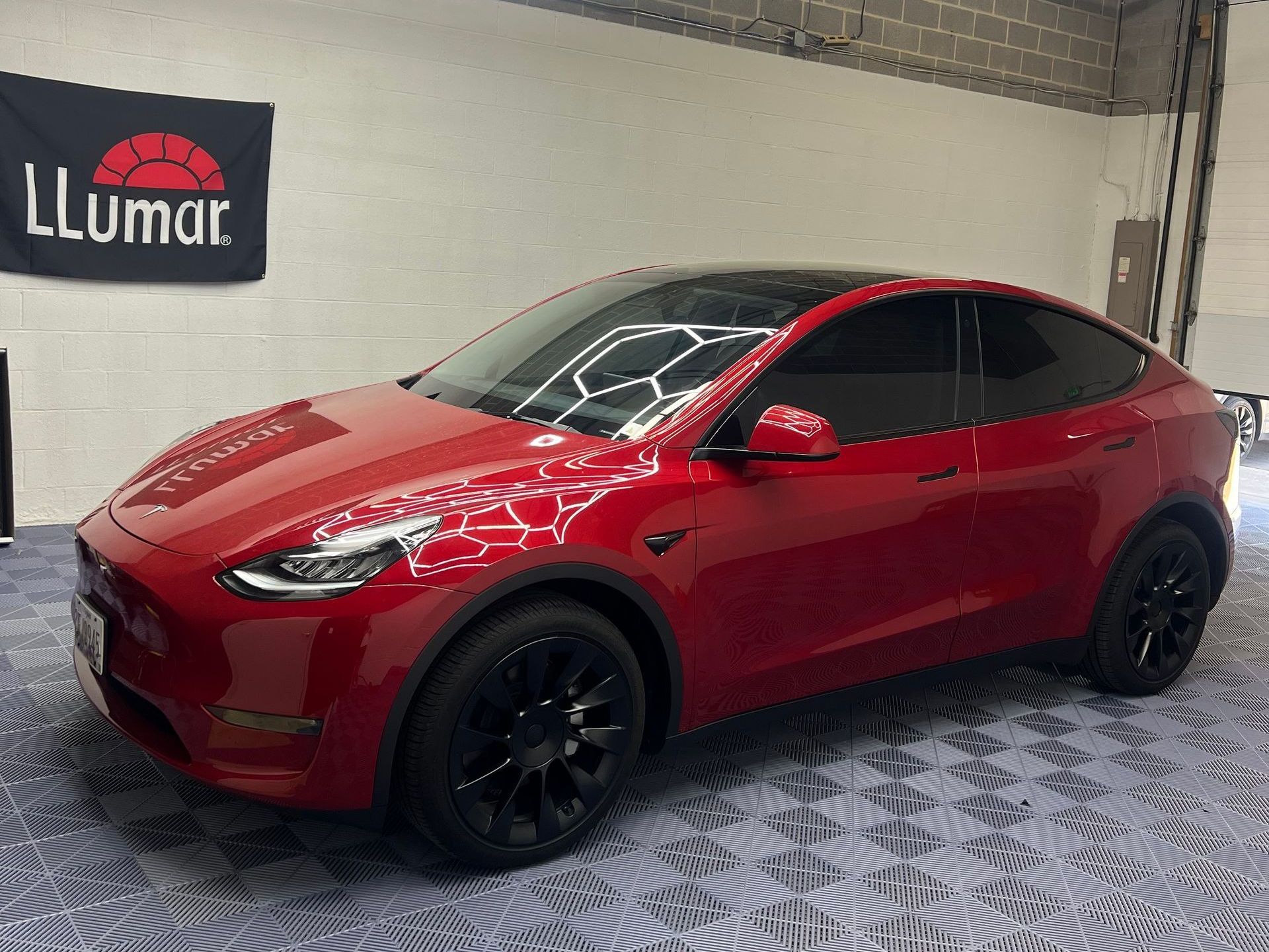 Red Tesla SUV in a showroom with black wheels and tinted windows