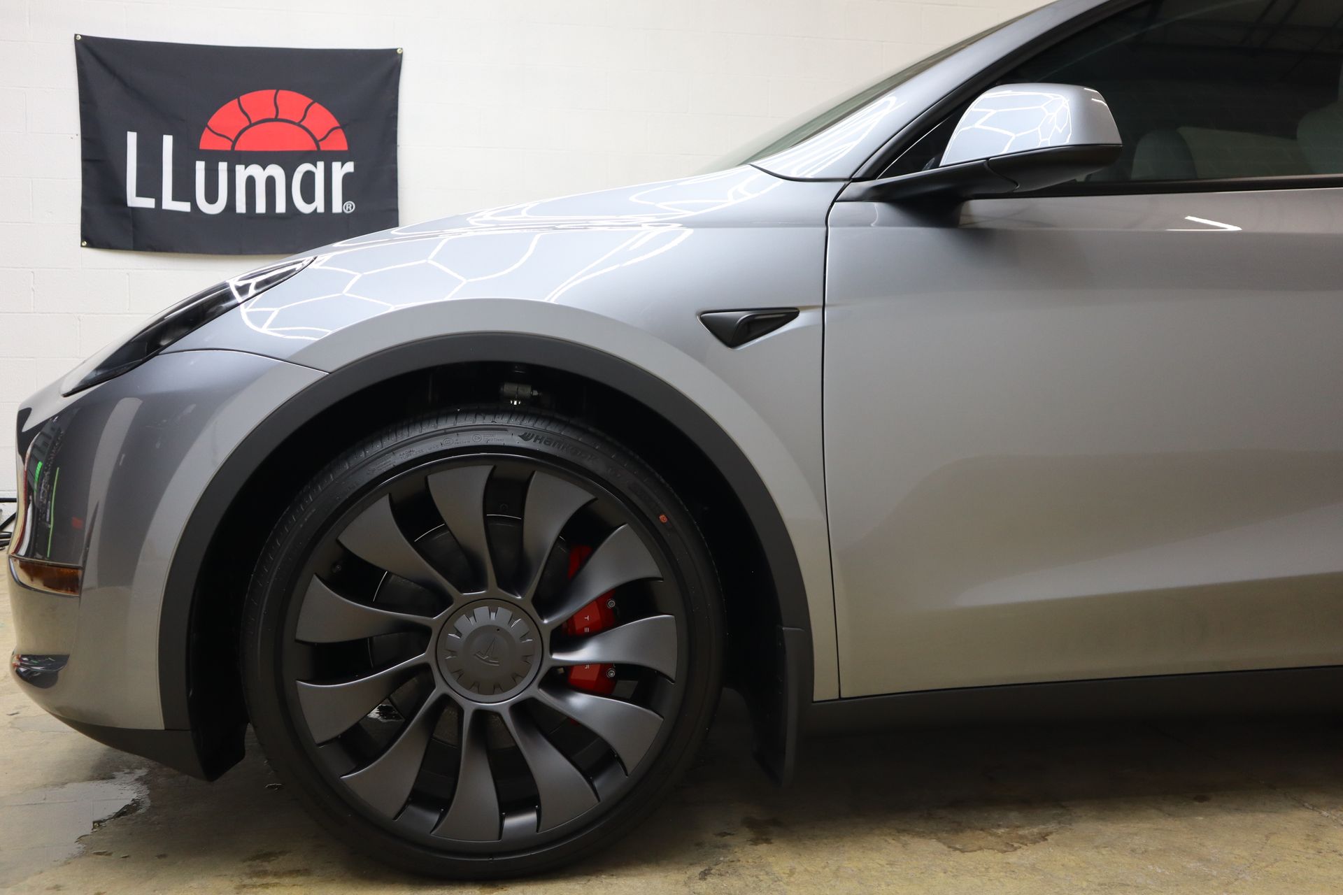 A person is applying a protective film to the hood of a car.