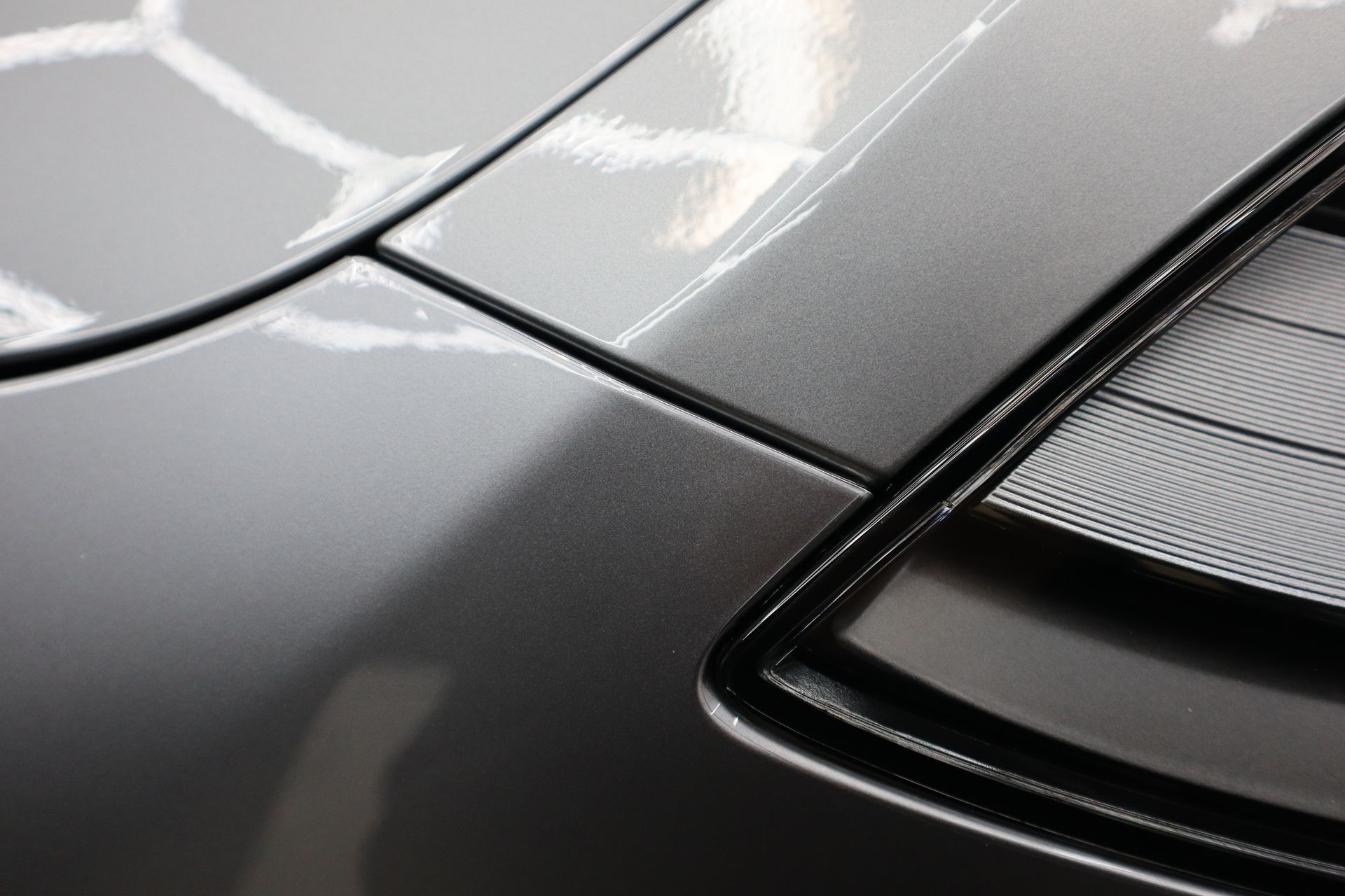 A close up of a car 's hood and tail light.