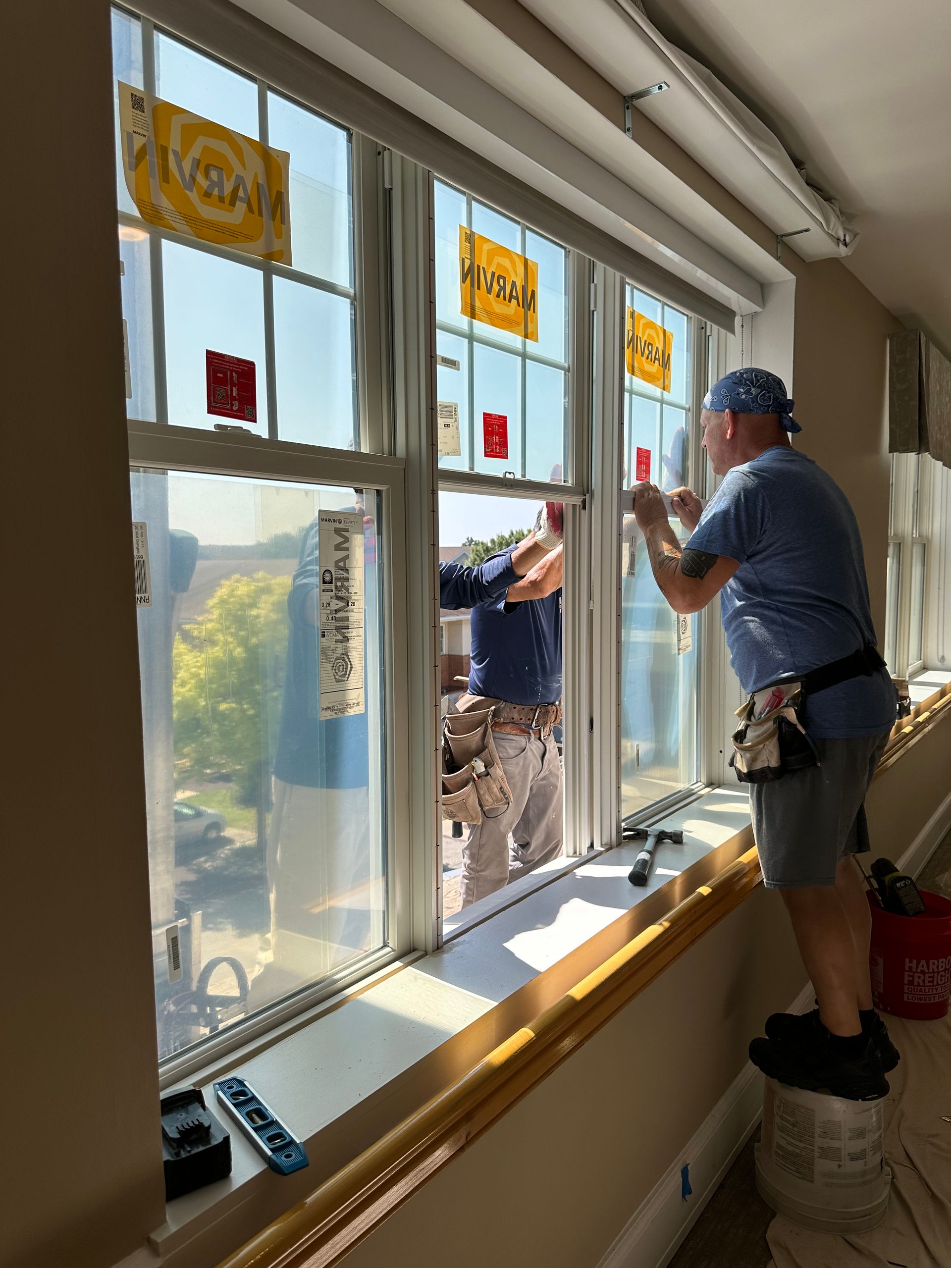 Two men are working on a window in a room.