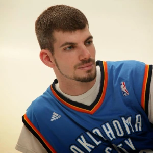 Man wearing Oklahoma City Thunder jersey looking off-camera, light skin, short brown hair.