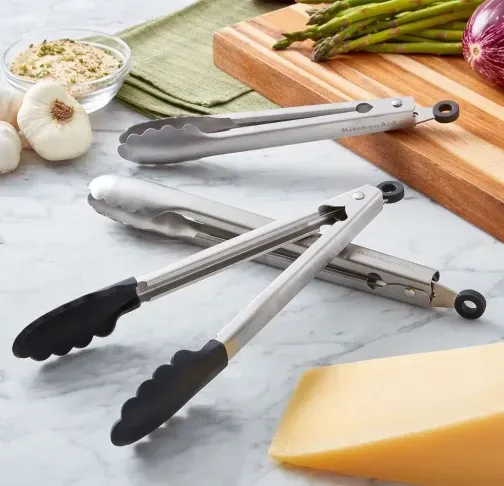 Um par de pinças sobre uma mesa ao lado de uma tábua de cortar