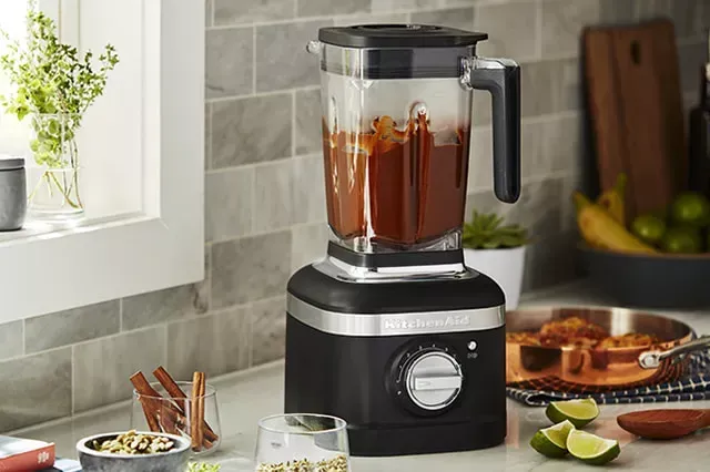 Um liquidificador kitchenaid está em um balcão de uma cozinha.