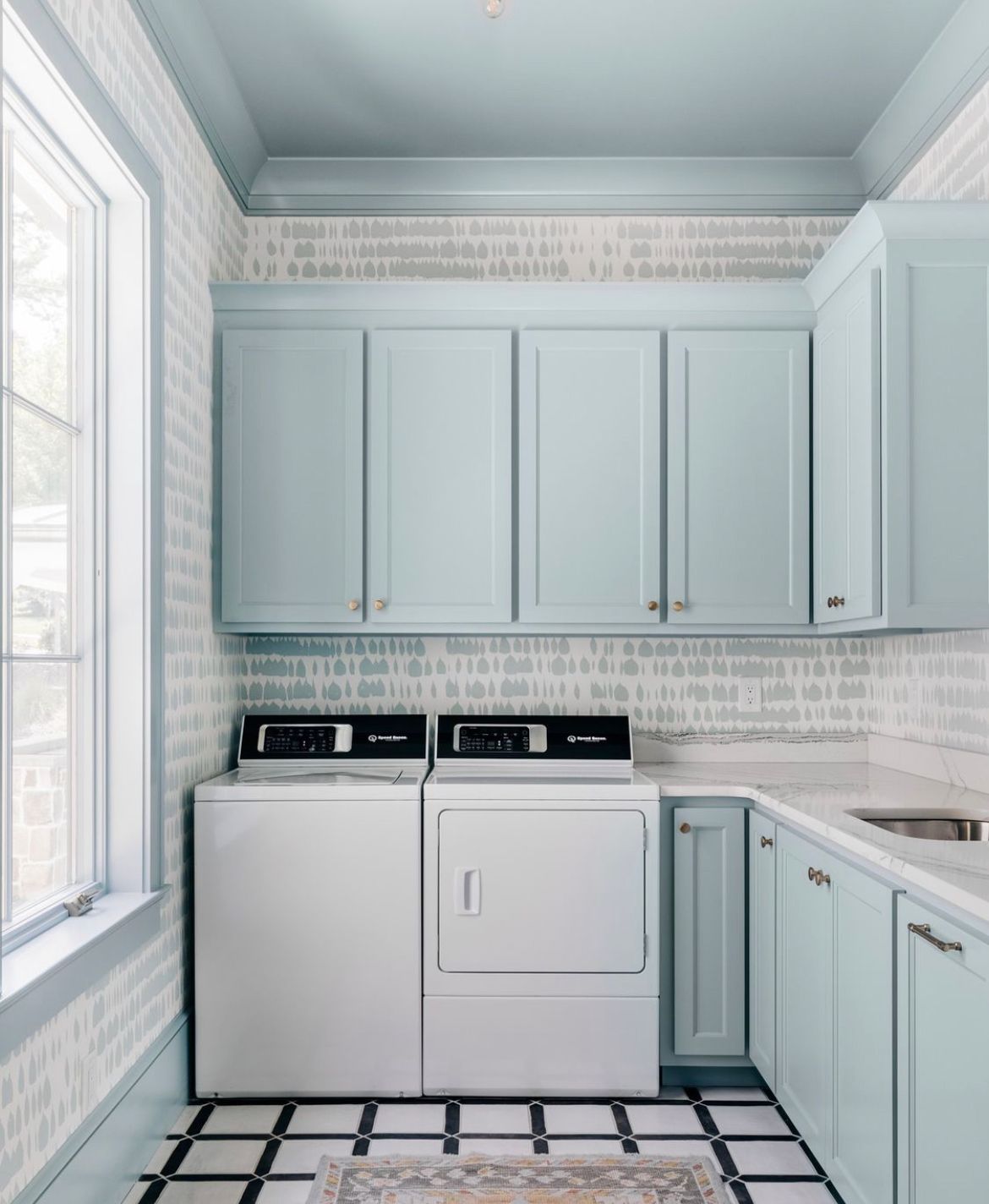 Uma lavanderia com lavadora e secadora e armários azuis.