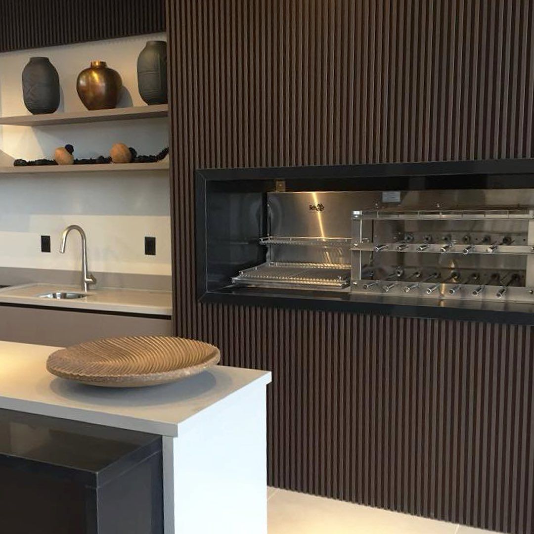 Uma cozinha com parede de madeira e grelha em inox.