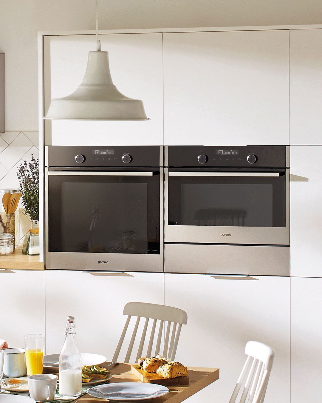 Uma cozinha com dois fornos e uma mesa com comida