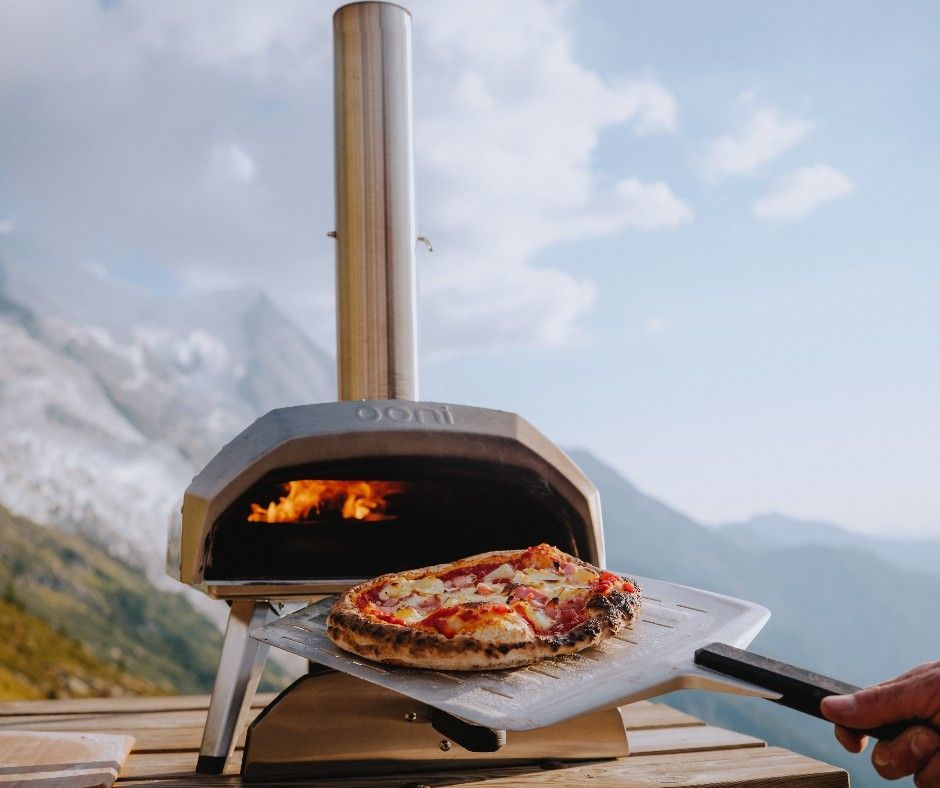 Uma pessoa está tirando uma pizza de um forno ao ar livre