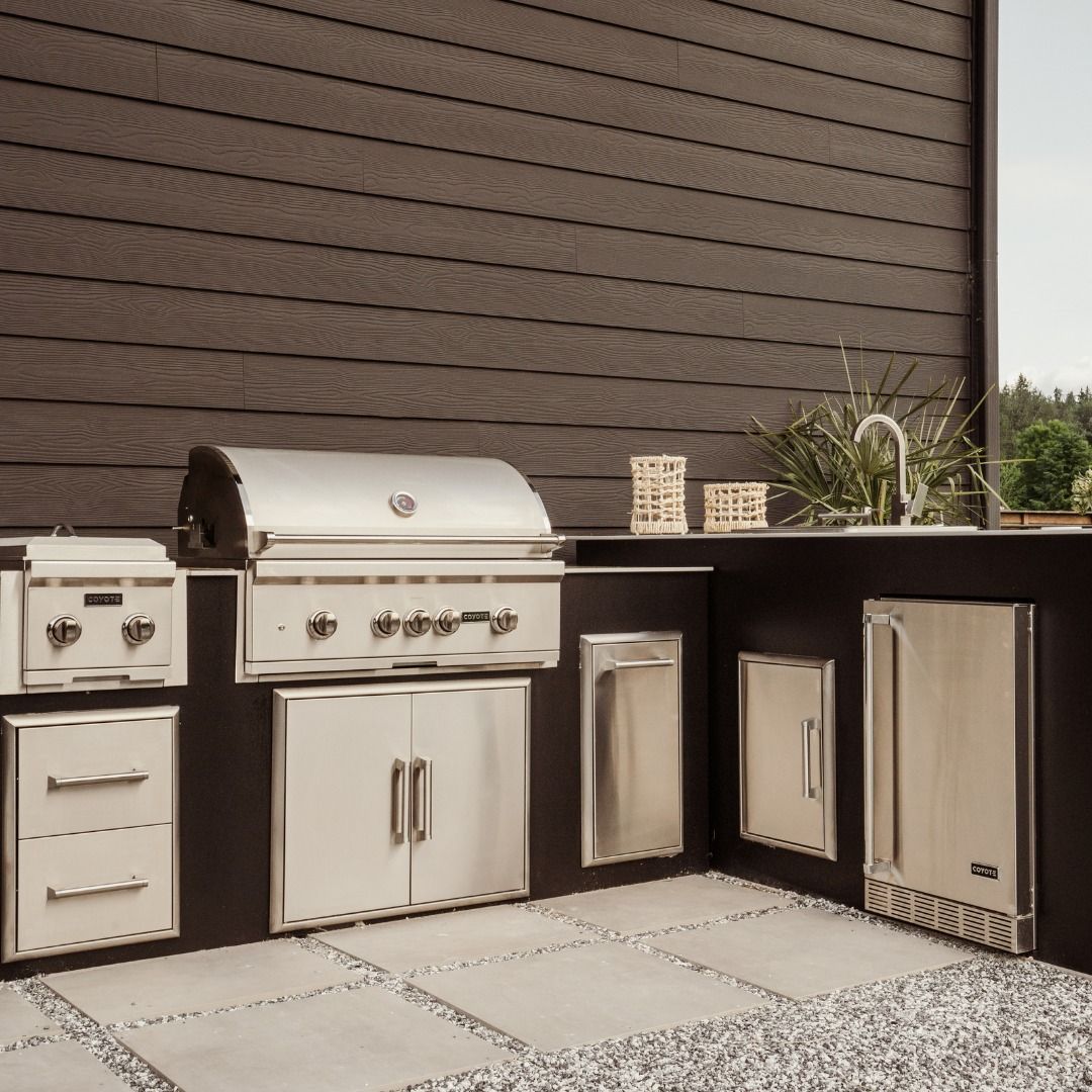 Uma cozinha externa com armários de aço inoxidável e churrasqueira