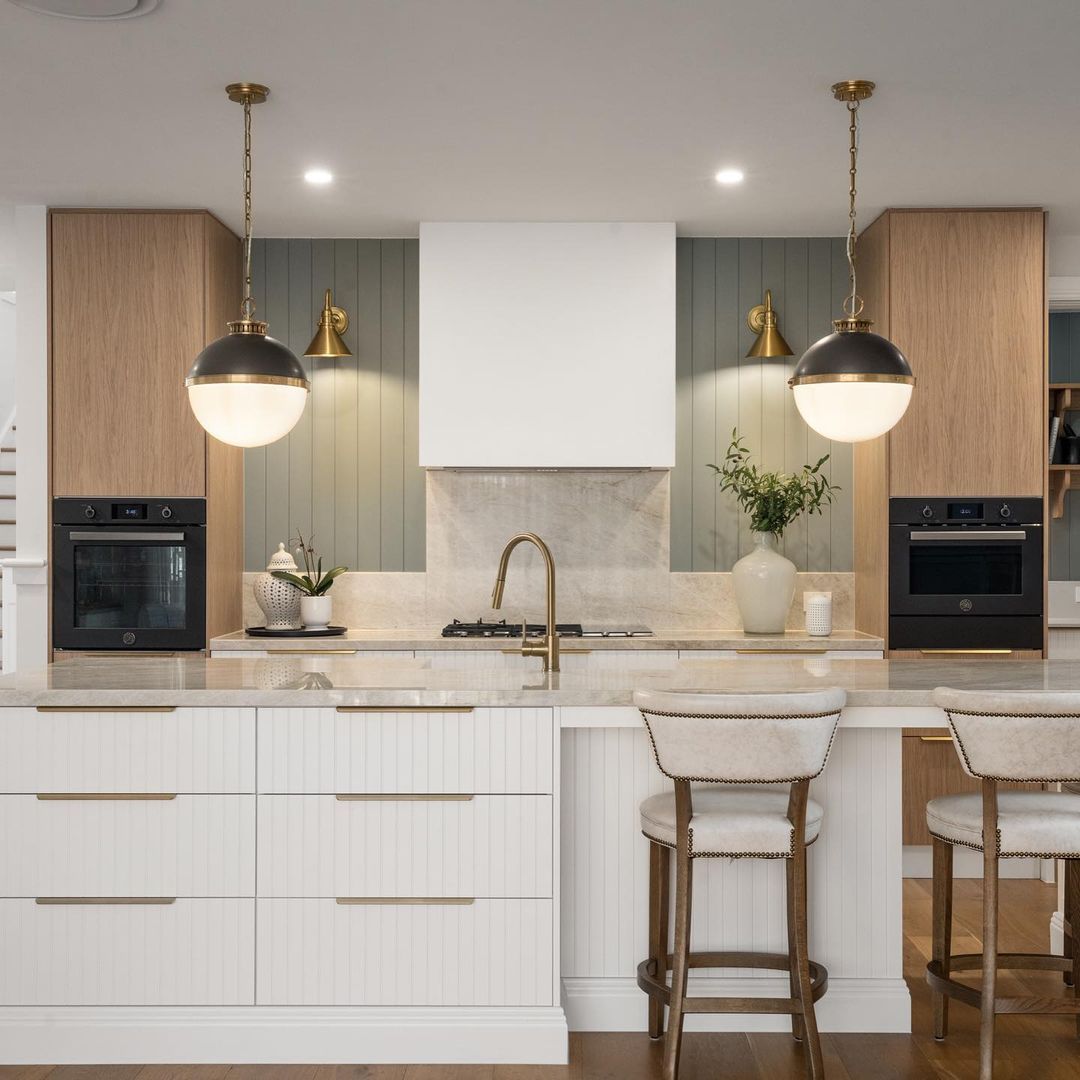 Uma cozinha com armários brancos e paredes de madeira