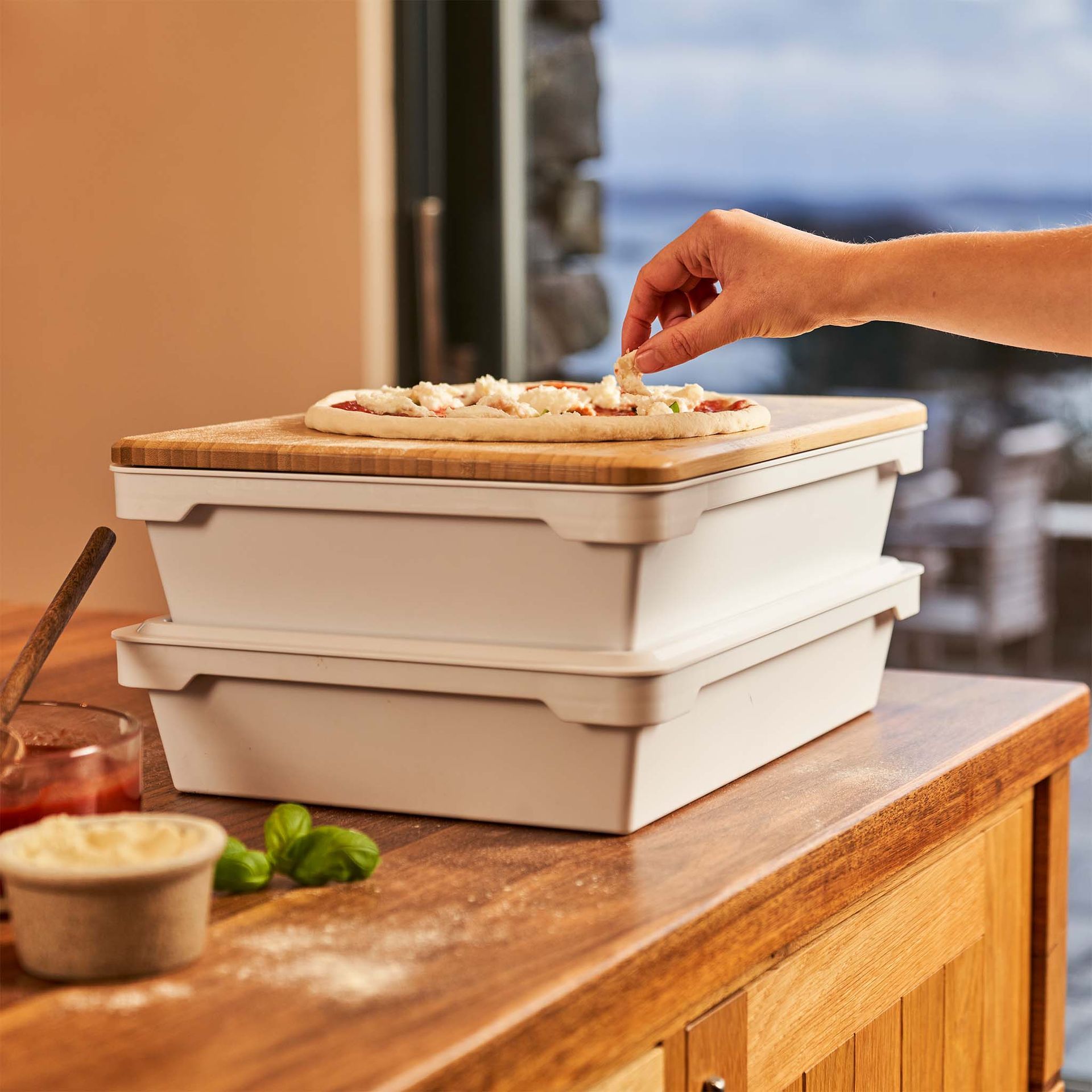 Uma pessoa está colocando uma pizza em uma tábua de madeira.