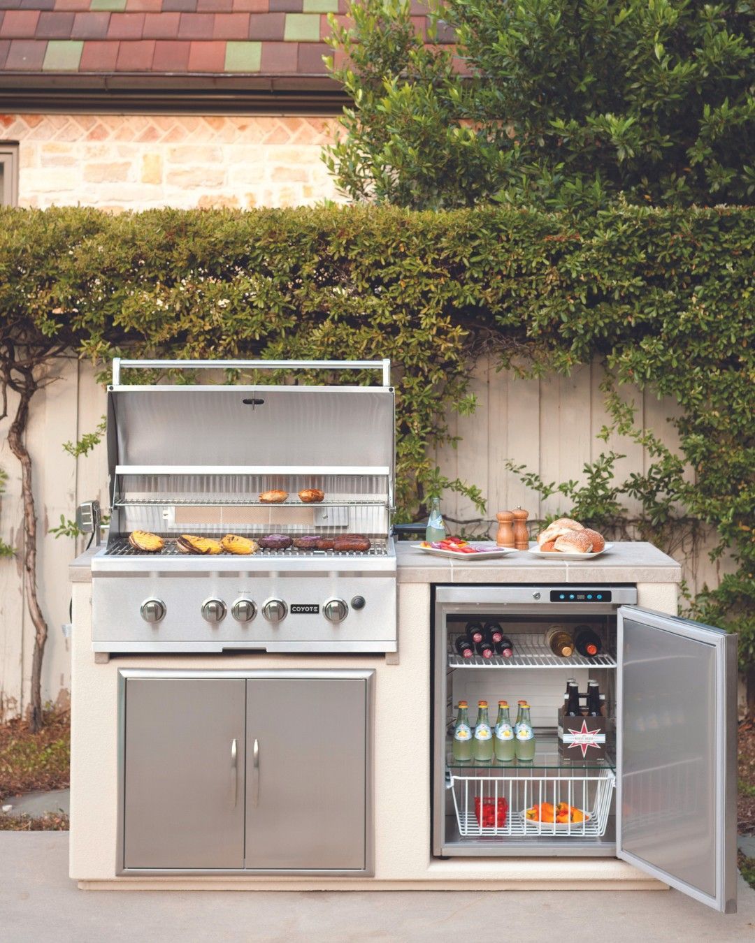 Uma cozinha ao ar livre com churrasqueira e geladeira