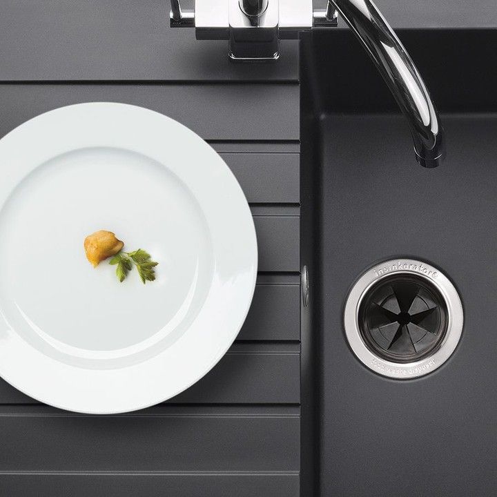 Um prato branco com um pedaço de comida ao lado de uma pia preta