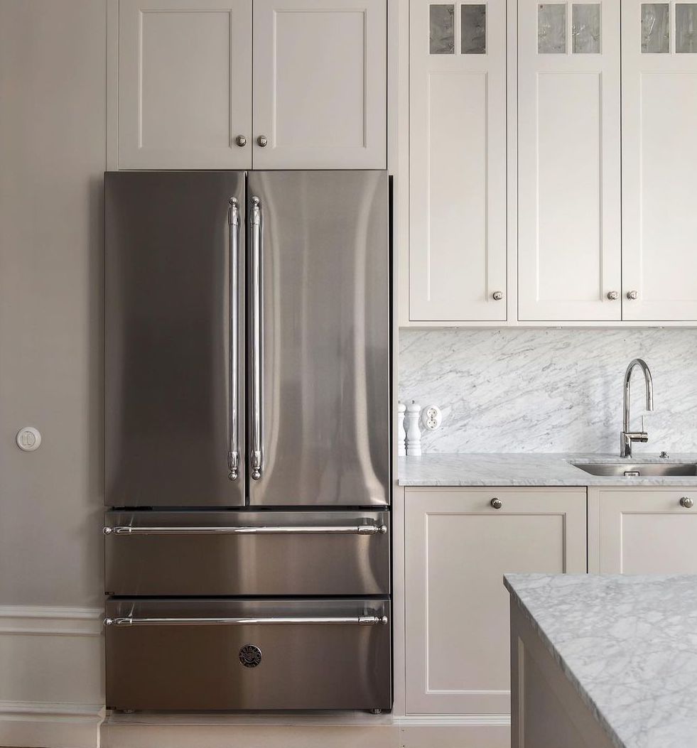 Uma cozinha com armários brancos e geladeira de aço inoxidável