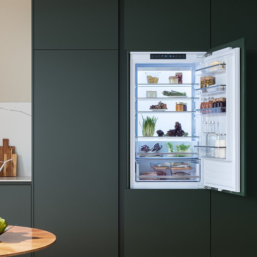 Uma geladeira com a porta aberta e muita comida dentro.