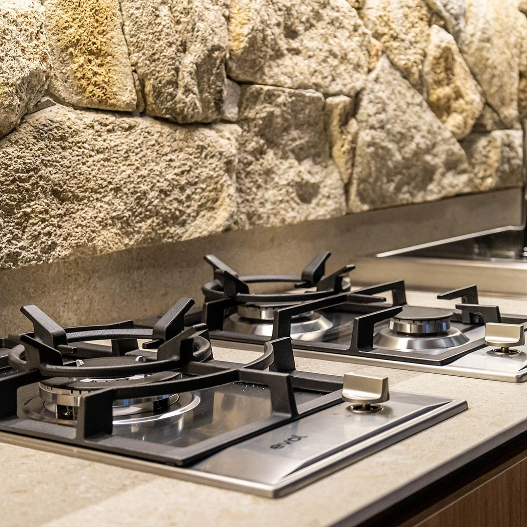 Uma cozinha com fogão e pia em frente a uma parede de pedra.