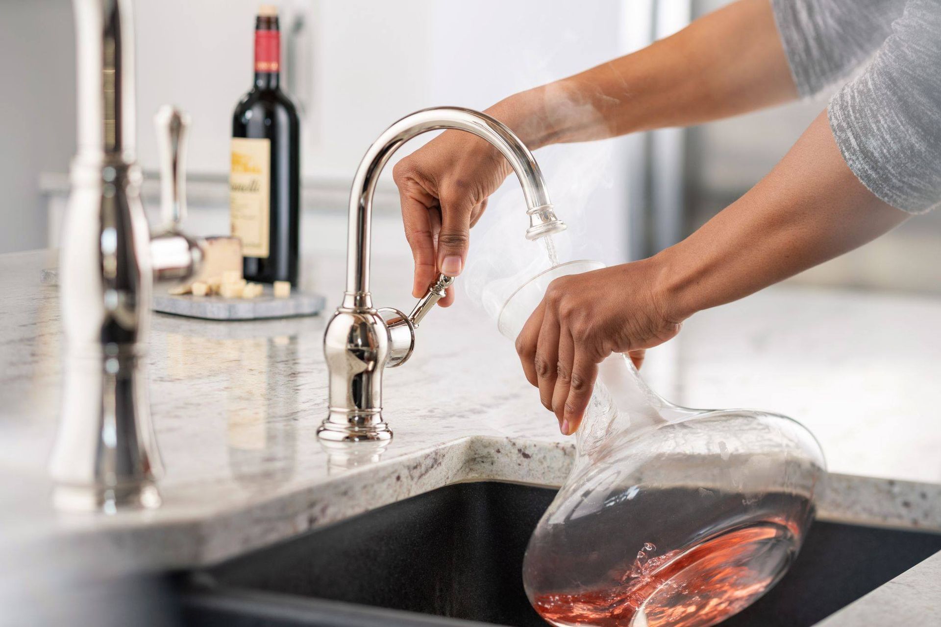 Uma pessoa está servindo uma taça de vinho em uma pia.