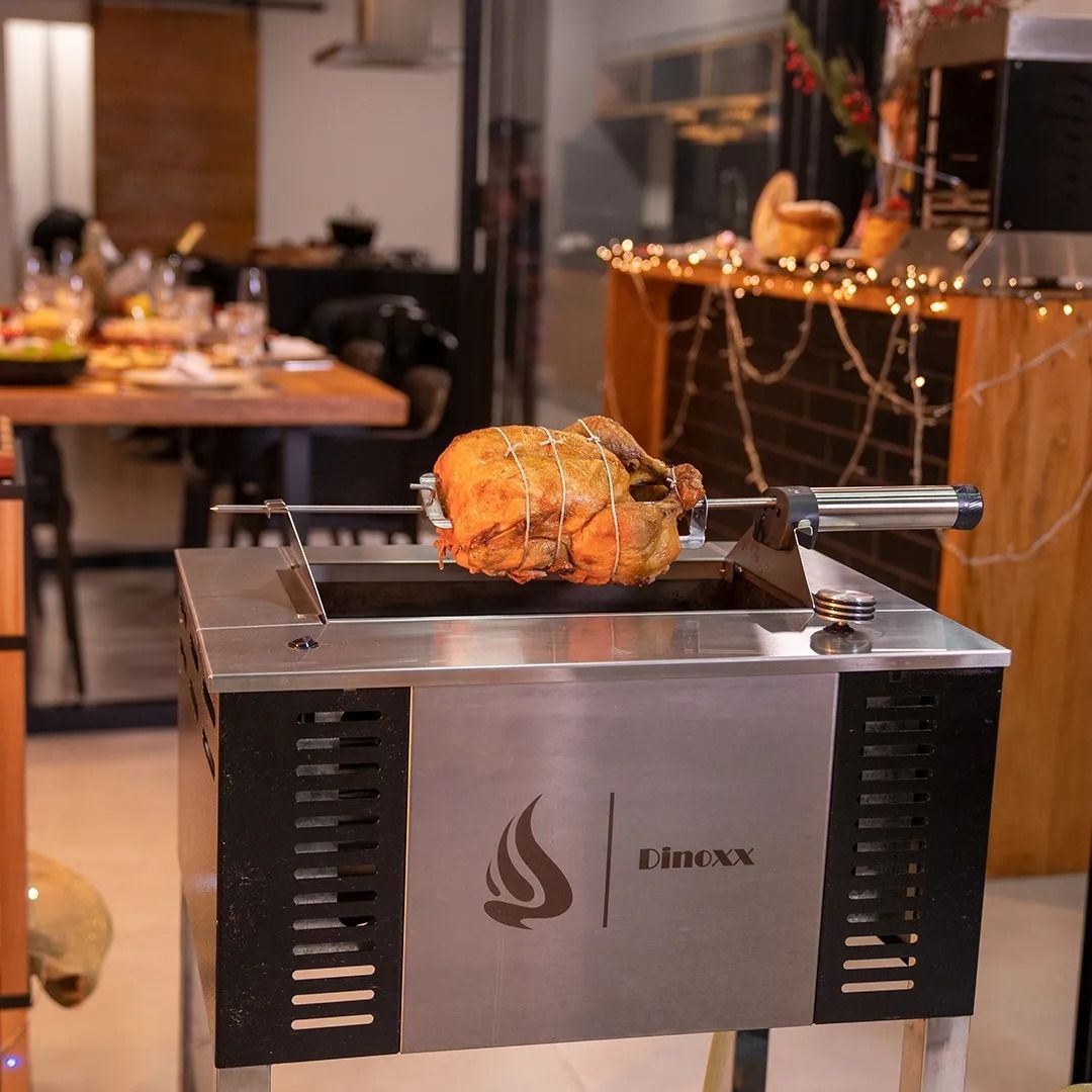 Um frango está cozinhando em uma grelha de aço inoxidável