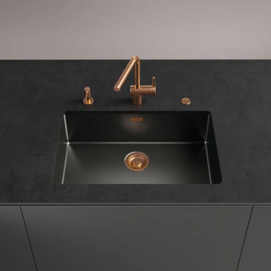 Uma pia de cozinha preta com torneira de cobre