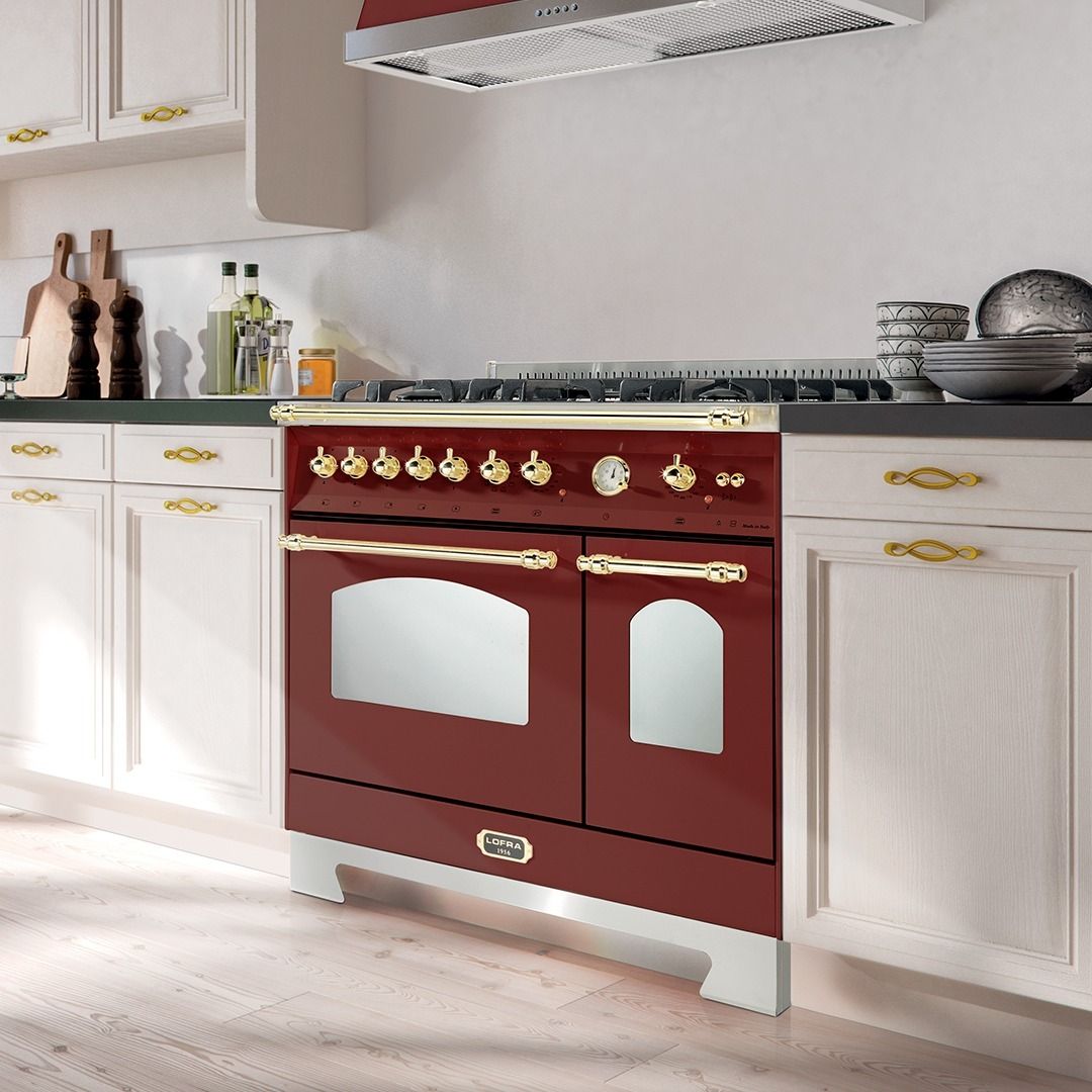 Uma cozinha com fogão vermelho e armários brancos