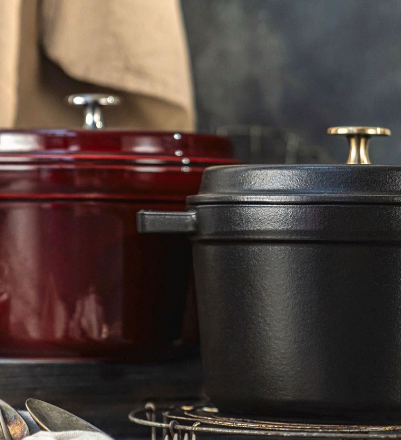 Um pote preto está ao lado de um pote vermelho sobre uma mesa.