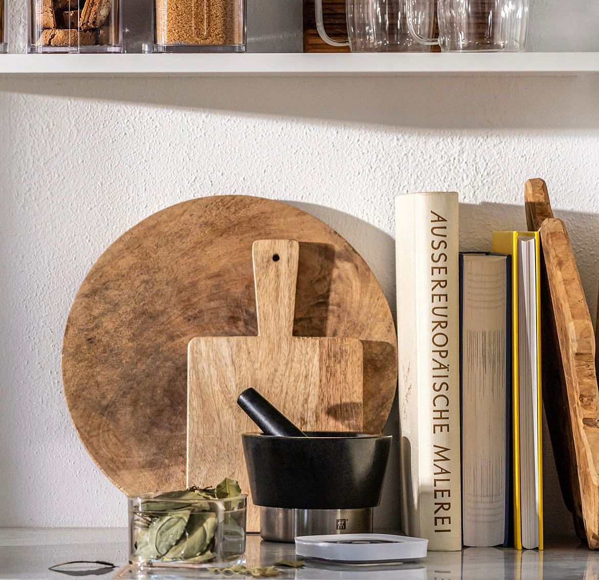 Uma prateleira com tábuas de corte e almofariz e pilão