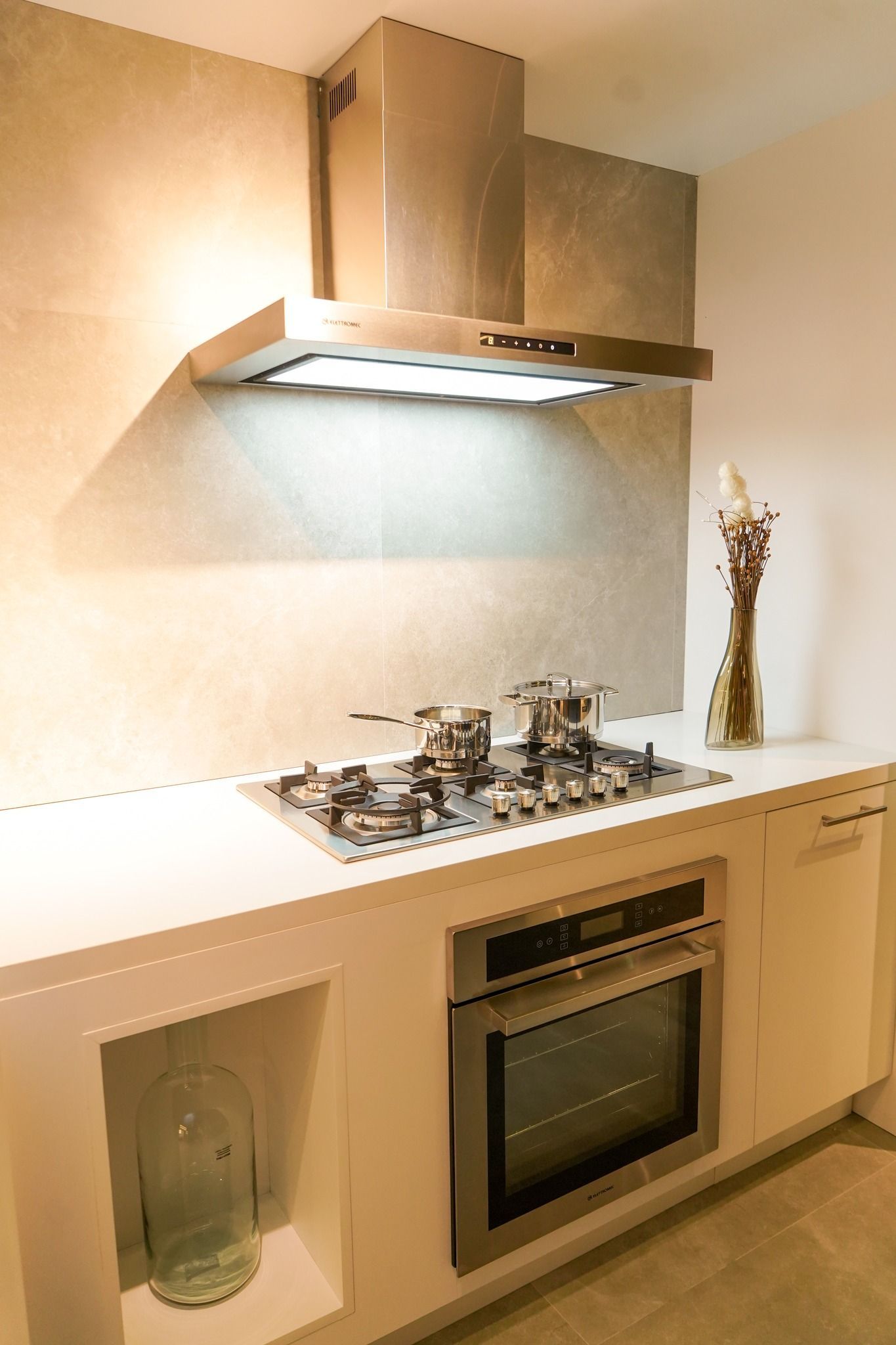 Uma cozinha com fogão, forno e exaustor por cima.