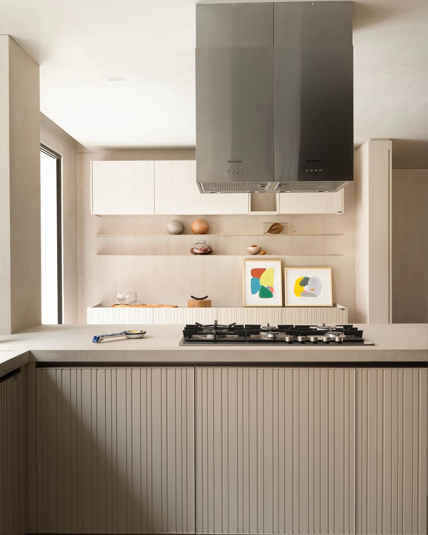 Uma cozinha com fogão, forno e exaustor por cima.