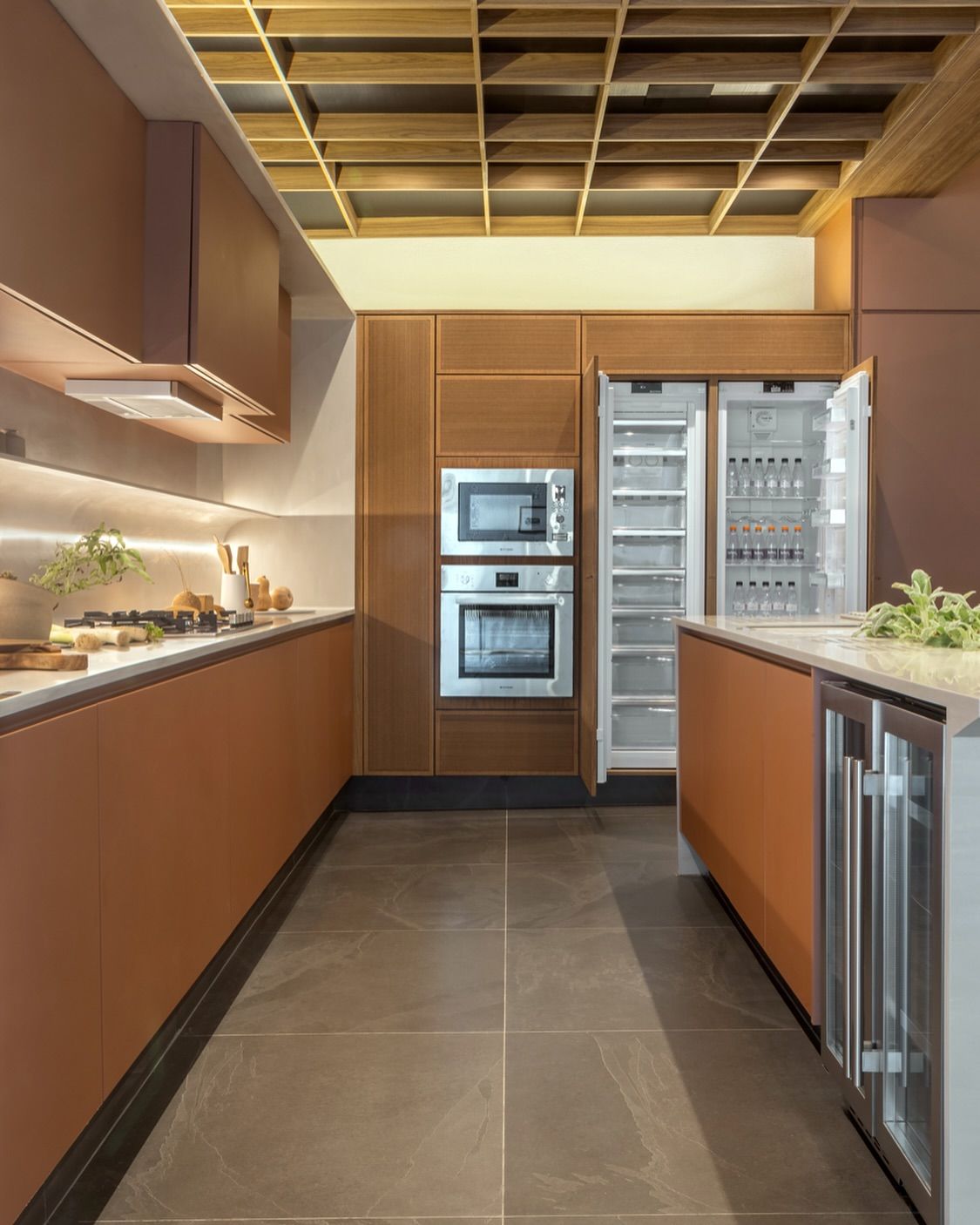 Uma cozinha com armários marrons, eletrodomésticos de aço inoxidável, geladeira e micro-ondas.