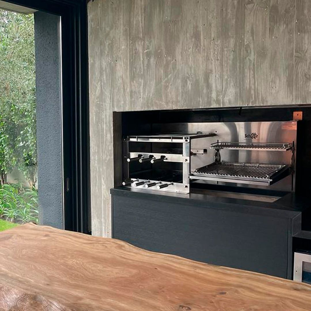 Uma cozinha com uma grande mesa de madeira e churrasqueira de aço inoxidável.