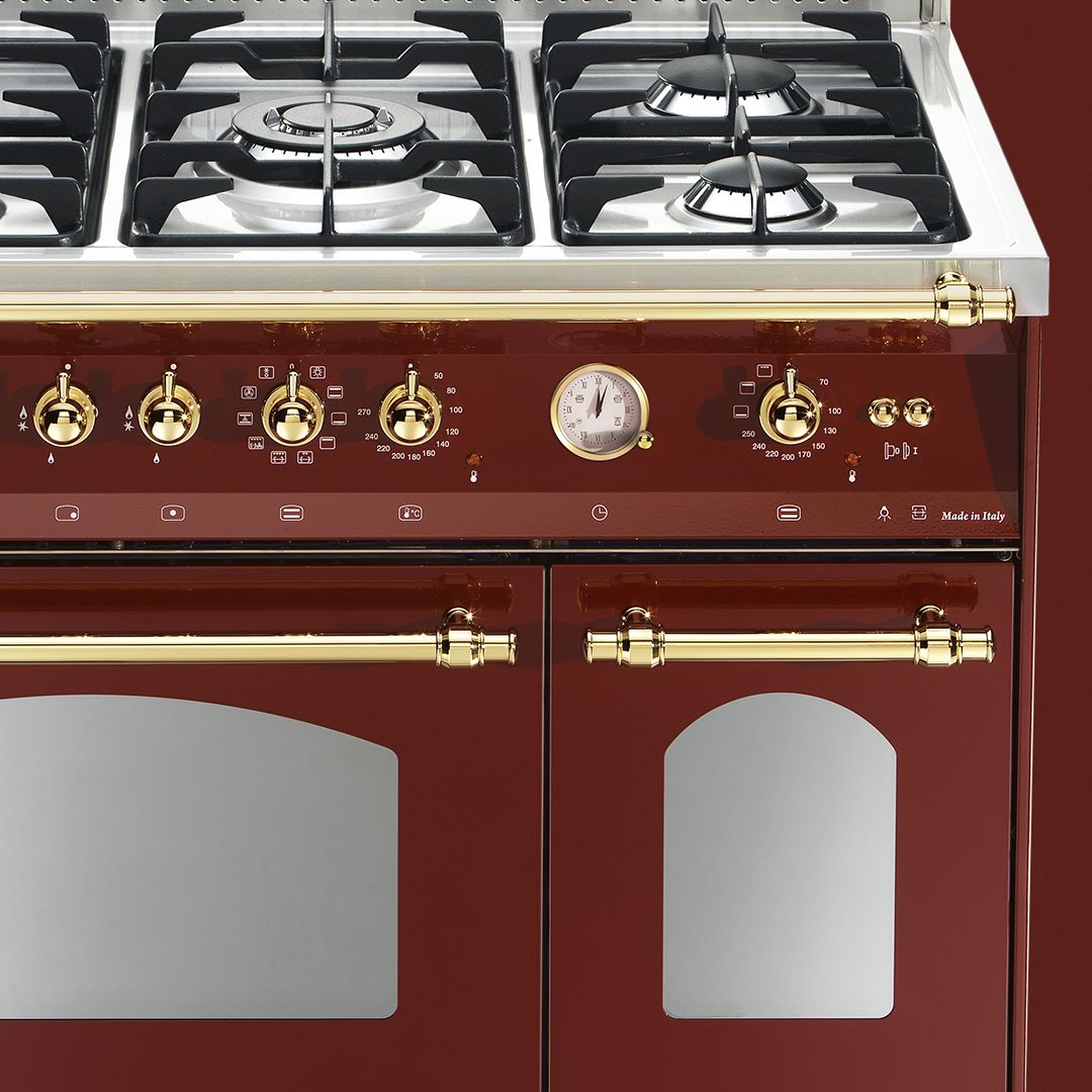 Um forno vermelho com alças e botões dourados