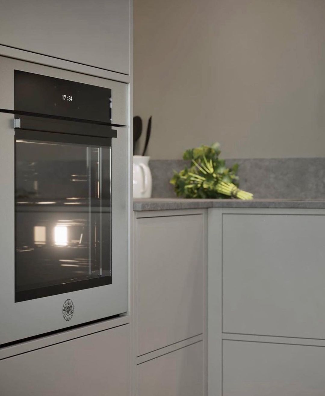 Uma cozinha com forno de aço inoxidável e um monte de brócolis na bancada.